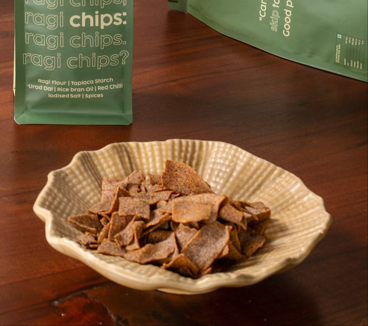 Ragi chips in a bowl with green packaging on a wooden table