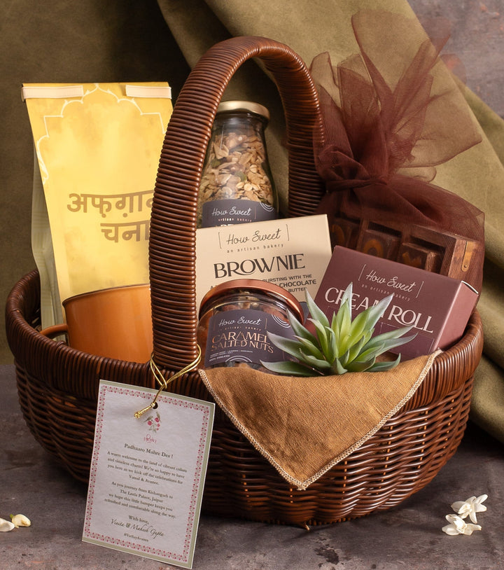 Gift basket with brownies, cookies, and a small plant on a textured surface with a green fabric background.