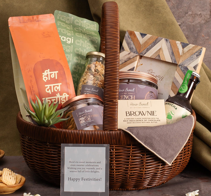 Gift basket with various items including a plant, cookies, and a bottle on a textured surface.