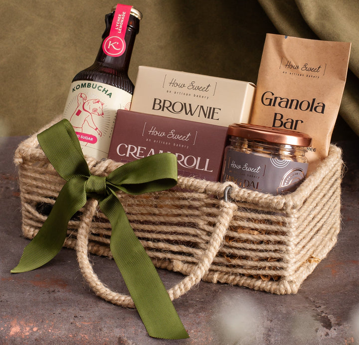 Gift basket with various items including a bottle, brownies, and granola bar on a textured surface.
